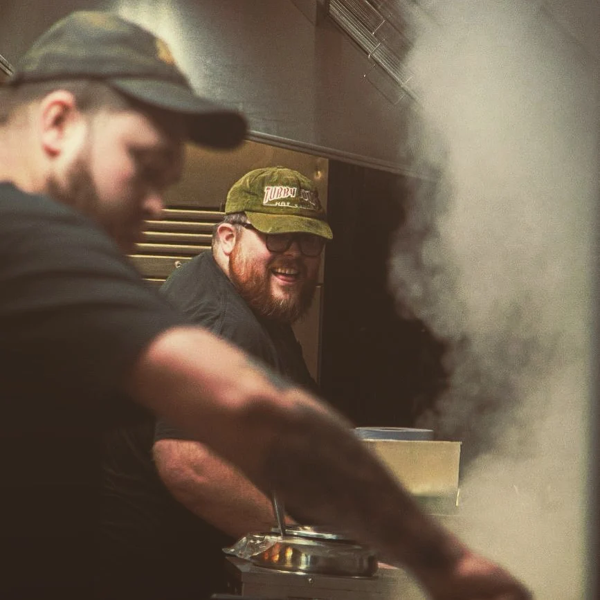 A photo of BBQ Society owner, Ben Williams smiling whilst operating a deep fat fryer